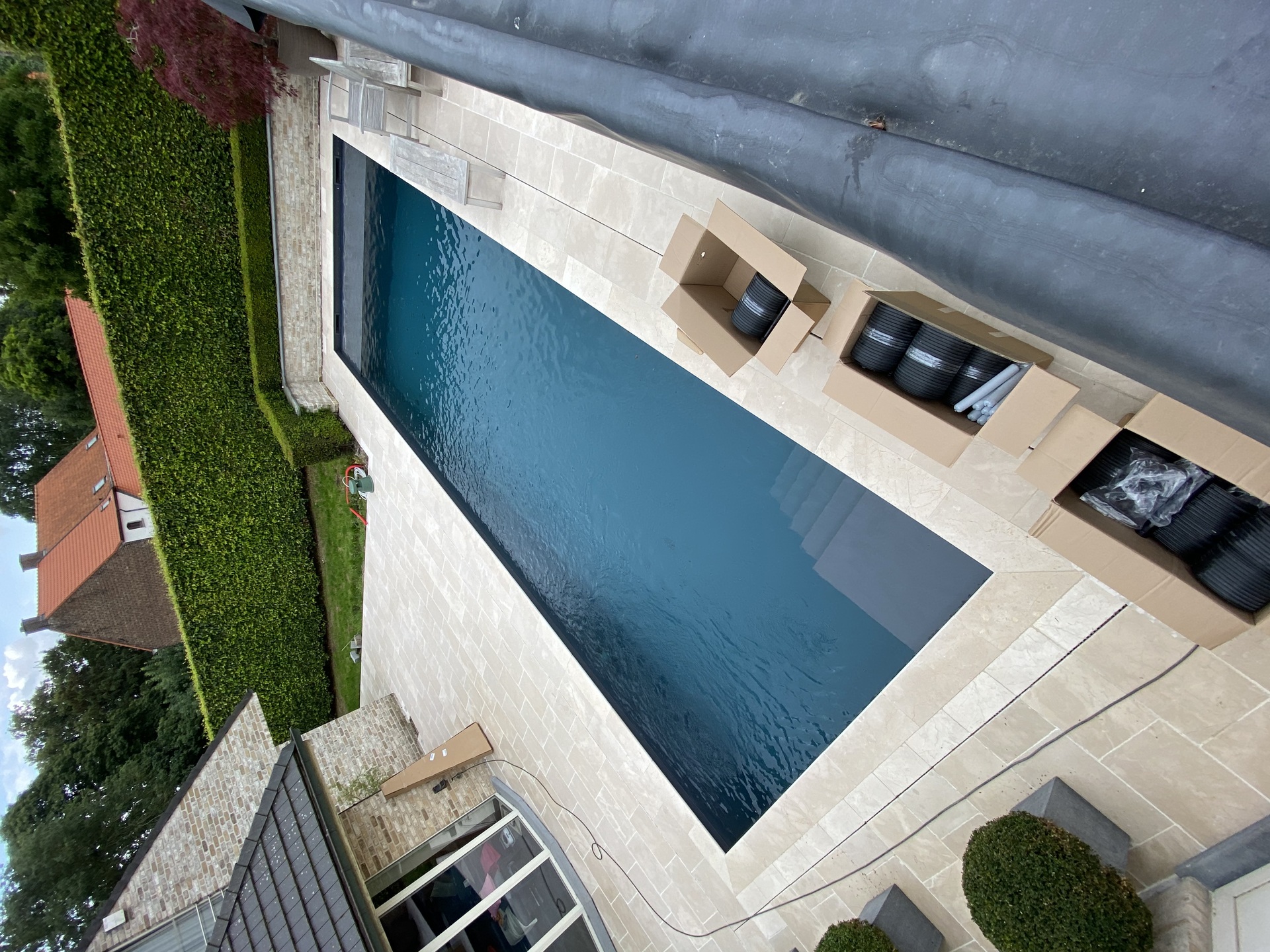 Modern rechthoekig zwembad met donkerblauw water en ruim terras van lichte natuursteen